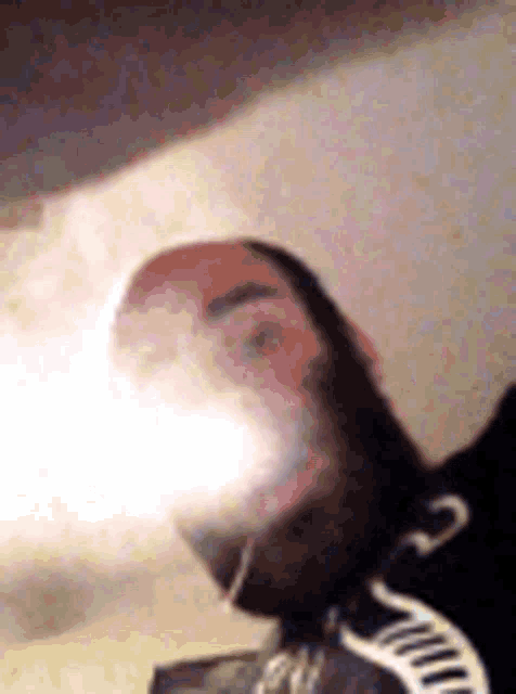 a man with a beard is smoking a cigarette while wearing a black shirt .