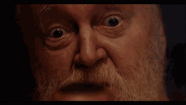 a close up of a man 's face with a beard and a surprised look on his face