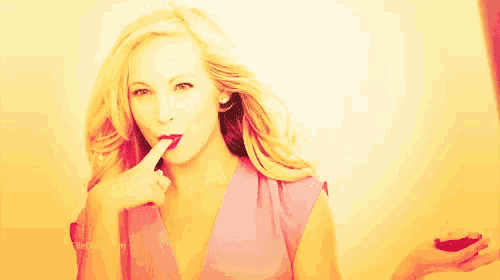 a woman is applying red lipstick to her lips while holding a lipstick in her hand .