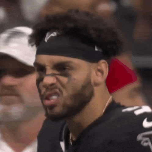 a football player wearing a headband with the letter v on it is making a funny face .