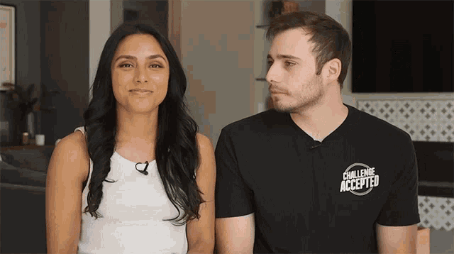 a man and a woman are sitting next to each other and the man has a shirt that says challenge accepted
