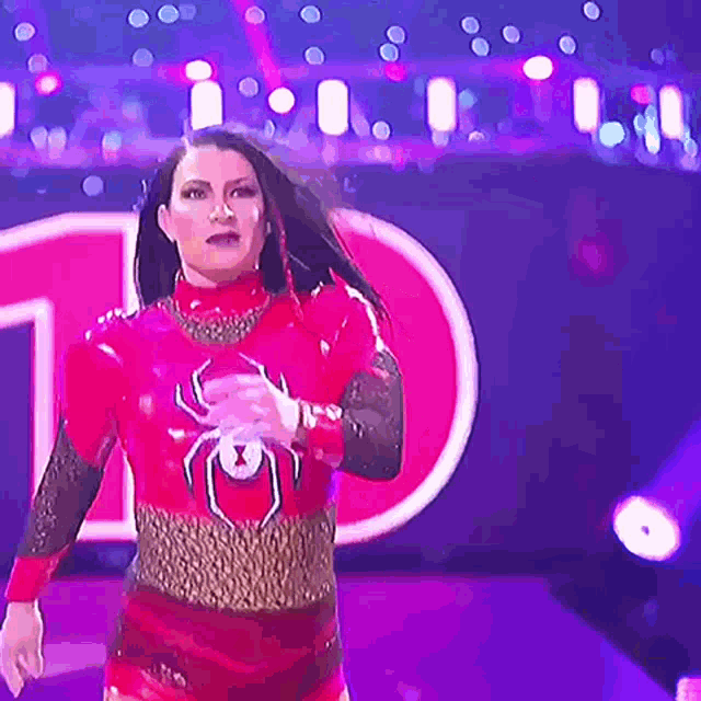 a woman in a red and gold costume with a spider on her chest is standing on a stage .