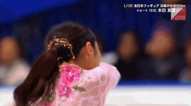 a female figure skater is wearing a pink dress with a floral pattern .