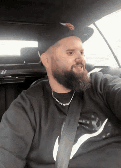 a man with a beard is wearing a hat and a black nike shirt