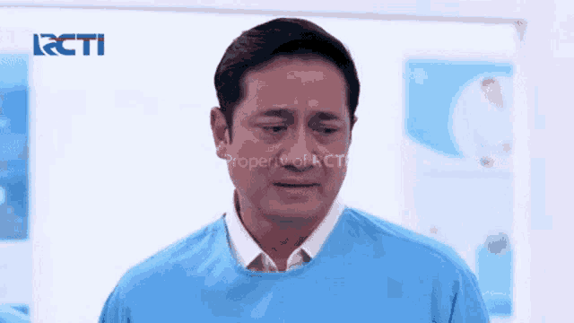 a man in a blue scrub top is crying in a hospital room