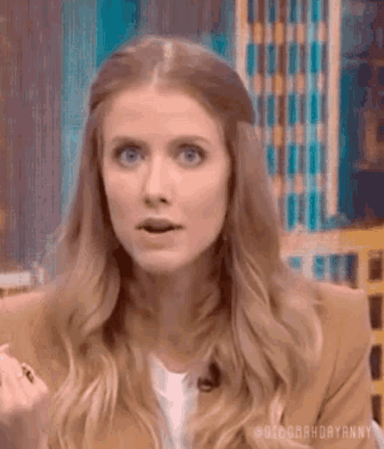 a woman with long blonde hair is making a funny face while sitting on a chair .