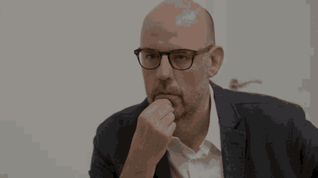 a bald man with glasses and a beard is making a face