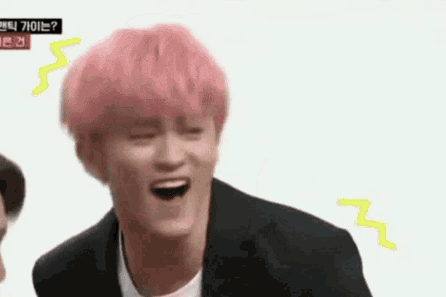 a man with pink hair is making a funny face while wearing a suit and tie .