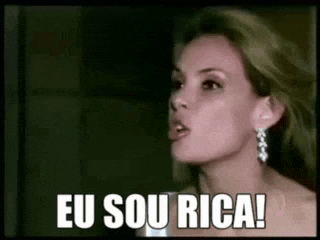 a woman is making a funny face and saying `` eu sou rica '' in a dark room .