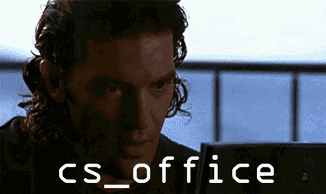 a man sitting in front of a laptop with the words cs_office written on the screen