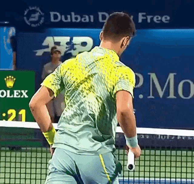 a man holding a tennis racquet in front of a sign that says olex