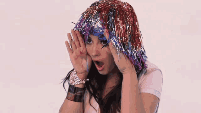 a woman wearing a hat of tinsel covering her face with her hands