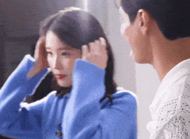 a man and a woman are standing next to each other and the woman is adjusting her hair .