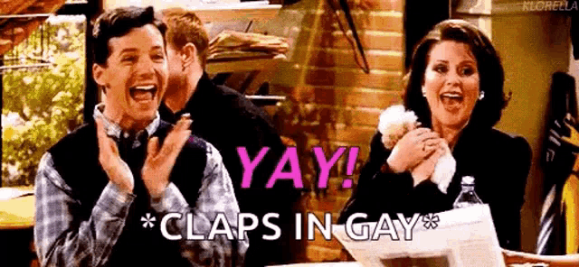 a man and a woman are clapping while sitting at a table with a newspaper .