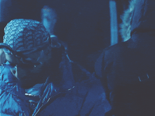 a man wearing a bandana and sunglasses is in a dark blue room