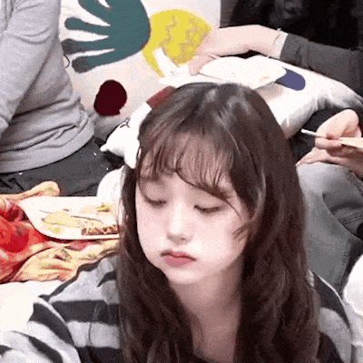 a young girl is sitting on a couch with a plate of food in her hand .