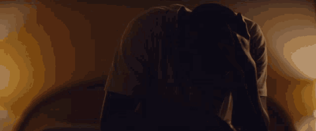 a man in a white shirt is covering his face with his hand