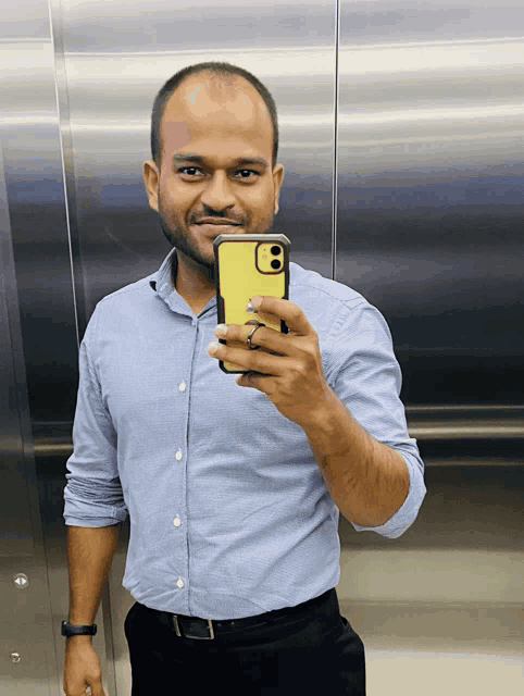 a man in a blue shirt is taking a picture of himself with his phone