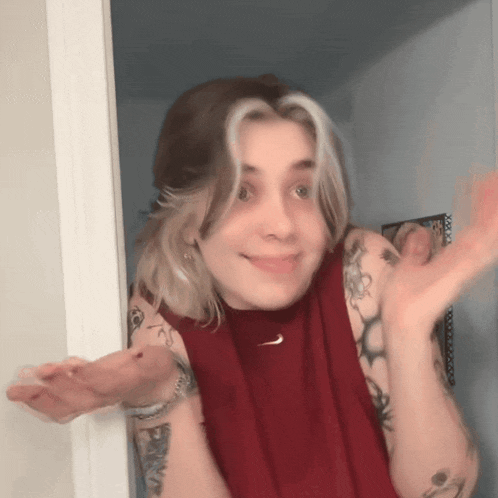 a woman with tattoos is wearing a red tank top with a nike logo on it .