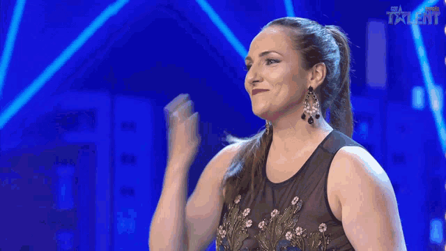 a woman stands on a stage with her arm in the air and the word talent is on the bottom right