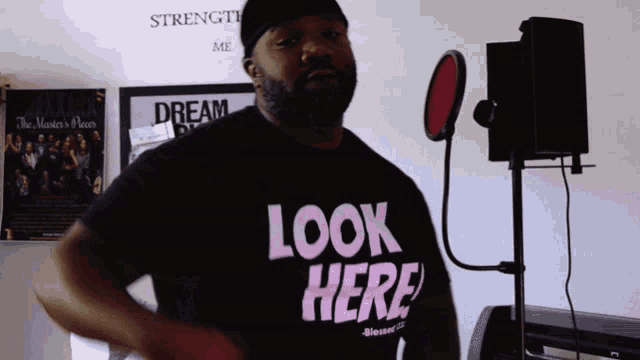 a man wearing a black t-shirt that says look here