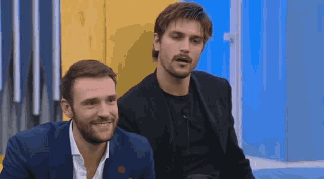 two men are sitting next to each other and smiling for the camera