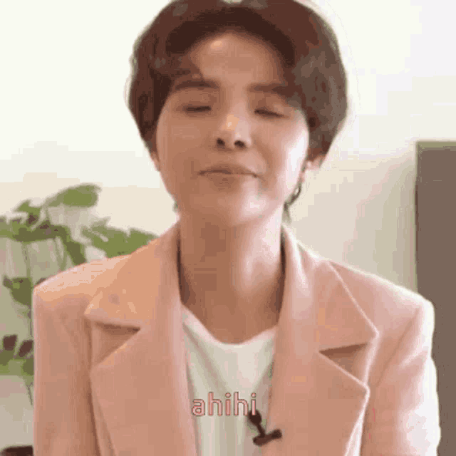 a woman wearing a pink jacket and a white shirt is making a funny face with her eyes closed .