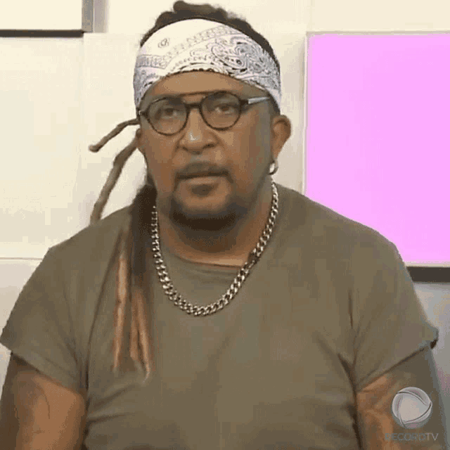 a man with dreadlocks and a bandana on his head is wearing glasses and a chain around his neck
