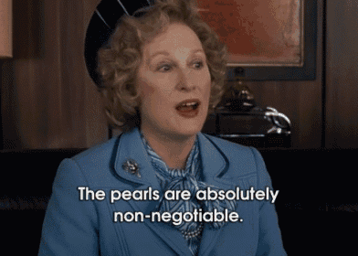a woman in a blue suit says the pearls are absolutely non negotiable