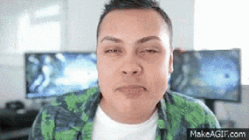 a man in a green shirt is making a funny face in front of a computer screen .