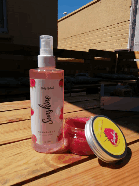 a bottle of sunshine body splash next to a jar of strawberry scrub