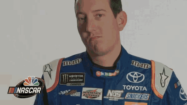 a man wearing a toyota and m & m 's racing uniform makes a funny face