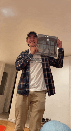 a man wearing a plaid shirt that says mabon holds up a picture