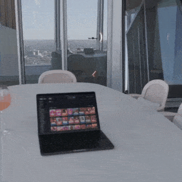 a laptop is open on a table with a glass of wine in the foreground