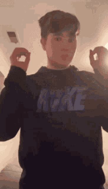 a boy wearing a black nike sweatshirt is making a funny face