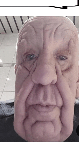 a close up of an older man 's face with a black shirt on