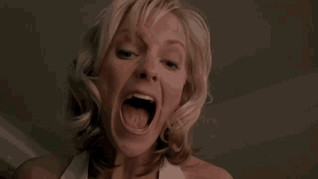 a woman with blonde hair is screaming with her mouth wide open