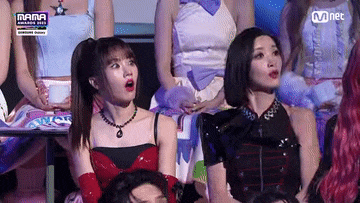 a group of women are sitting in a row watching a performance on stage .