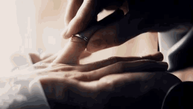 a close up of a person 's hands with a ring on their finger .