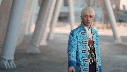 a man with blonde hair is wearing a blue jacket with the letter u on the front