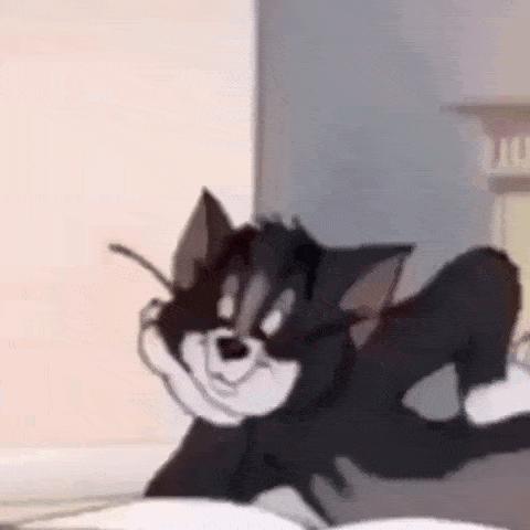 a cartoon cat is laying on a bed with his legs crossed and looking at the camera .