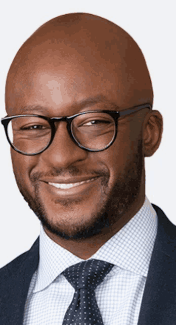 a bald man wearing glasses and a suit smiles