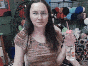 a woman is holding a bottle of water with a pink lid