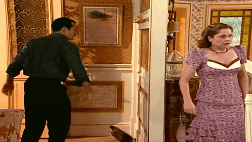a woman in a purple dress stands next to a man in a green shirt in a room with a menu on the wall