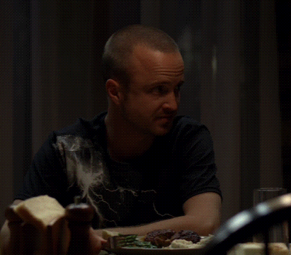 a man in a black shirt is sitting at a table with a plate of food