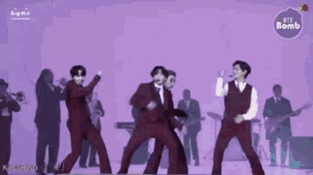 a group of men in suits and vests are dancing on a stage with a purple background that says ' bts bomb '