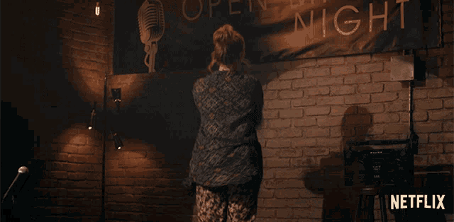 a woman is dancing in front of a brick wall with a netflix logo in the corner