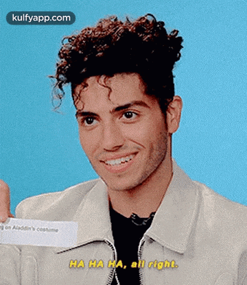 a young man with curly hair is smiling while holding a piece of paper that says ha ha ha all right .