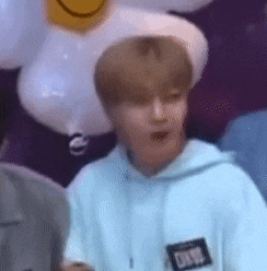a man in a blue hoodie is standing in front of balloons and a smiley face .