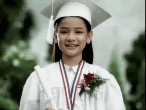 a young girl wearing a graduation cap and gown holds a diploma